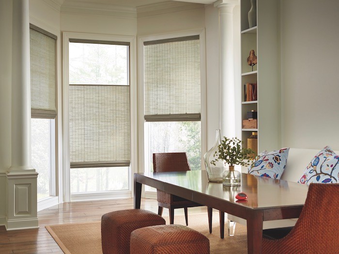 A dining room with burnt red furniture and muted green window shades.